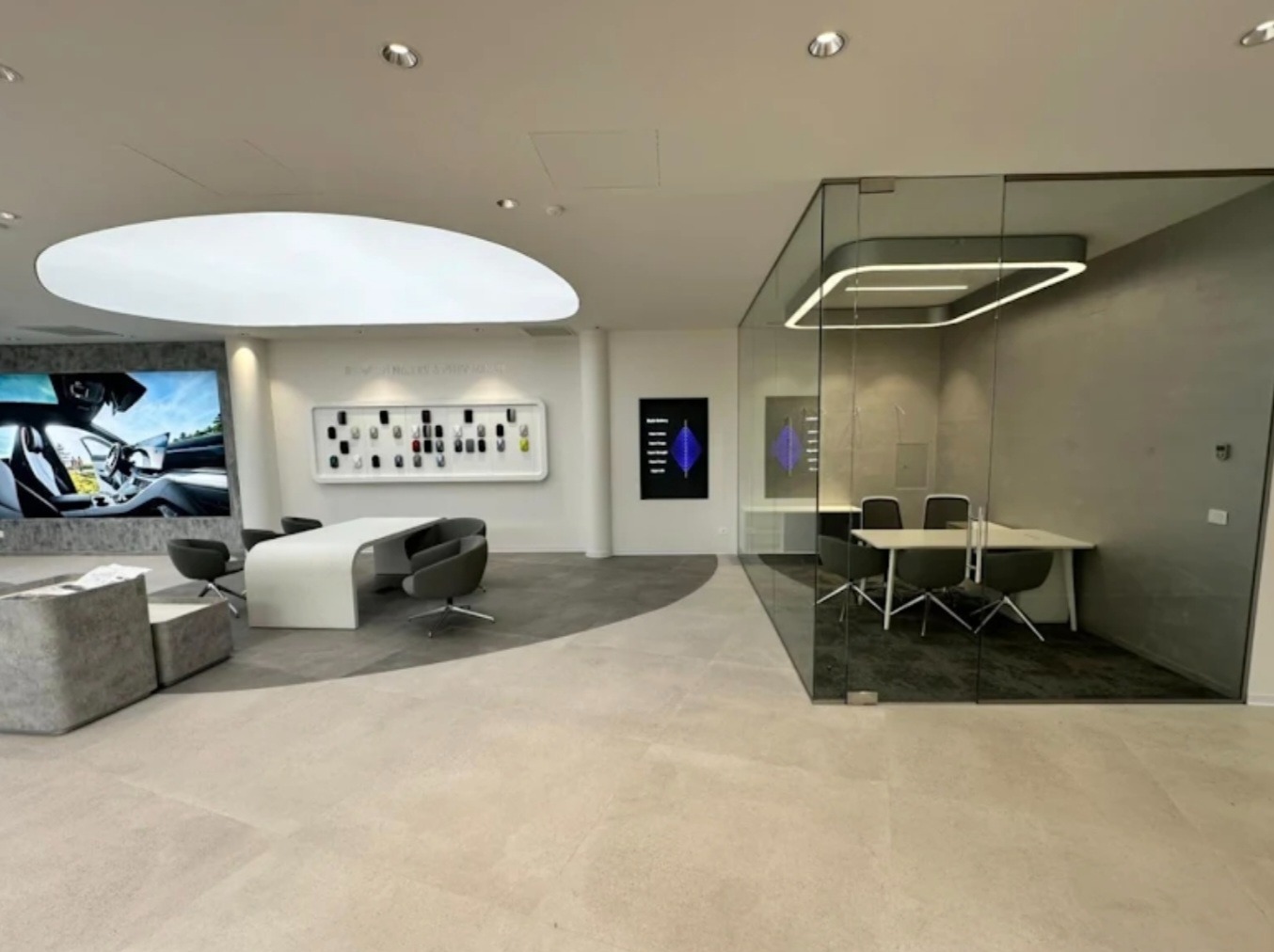 Nowoczesne biuro z przeszkloną ścianą działową i salą konferencyjną. Minimalistyczny design, jasne kolory, eleganckie meble. Widoczne detale wykończenia.