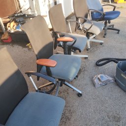 Norbert Ordon - Rząd używanych, biurowych krzeseł na kółkach, obok sprzęt do prania tapicerki. Widoczne ślady użytkowania. Przygotowanie do czyszczenia.