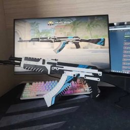 Adrian Pruski - Model AK-47 Vulcan, wydrukowany w 3D, leży na biurku obok klawiatury z podświetleniem RGB. Na monitorze widoczny ten sam model w grze. Detale w bieli, czerni i błękicie.