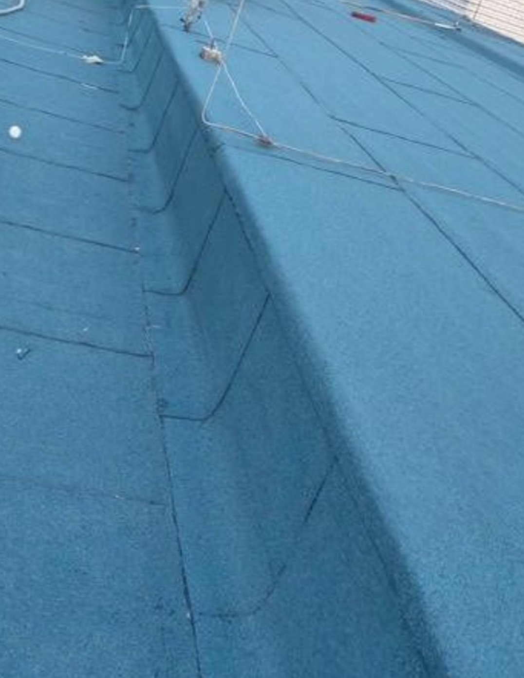 Niebieski dach pokryty papą termozgrzewalną z widocznymi łączeniami i systemem odgromowym. Ujęcie z bliska, ukazujące fakturę i detale.