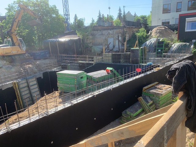 Wykonanie wykopu pod fundamenty z użyciem szalunków i zbrojenia. Na budowie widoczny jest także ciężki sprzęt budowlany.