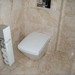 Marian Wincewicz wspólnik spólki cywilnej ROMASHKA; BETONIARSTWO- KAMIENIARSTWO MARIAN WINCEWICZ - Beżowe płytki imitujące marmur w łazience w Warszawie. Wisząca toaleta i pojemnik na papier toaletowy. Widoczne fugi i chromowane elementy.