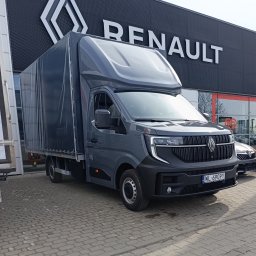 Dmytro Sveleba - Szary bus Renault z plandeką na tle salonu samochodowego. Widoczny numer rejestracyjny. Prezentacja pojazdu gotowego do transportu.