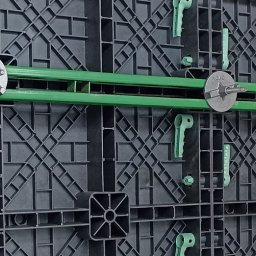 PLASPANEL Ltd - Szczegółowe ujęcie szalunku z tworzywa sztucznego z zielonym wzmocnieniem i metalowymi śrubami, ukazujące precyzję montażu i strukturę modułową.