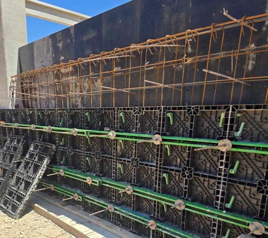 Szczegółowe ujęcie szalunku zbrojeniowego z widocznymi elementami konstrukcyjnymi i stalowymi prętami, przygotowanego do zalewania betonem.