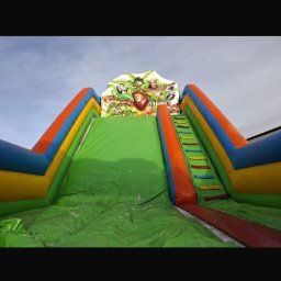 WIKTORIA WOJDA WIK-KOM - Kolorowa, dmuchana zjeżdżalnia z motywem zwierząt, widziana z dołu, z wyraźnie widoczną powierzchnią zjeżdżalni i schodkami. Idealna na imprezy plenerowe.