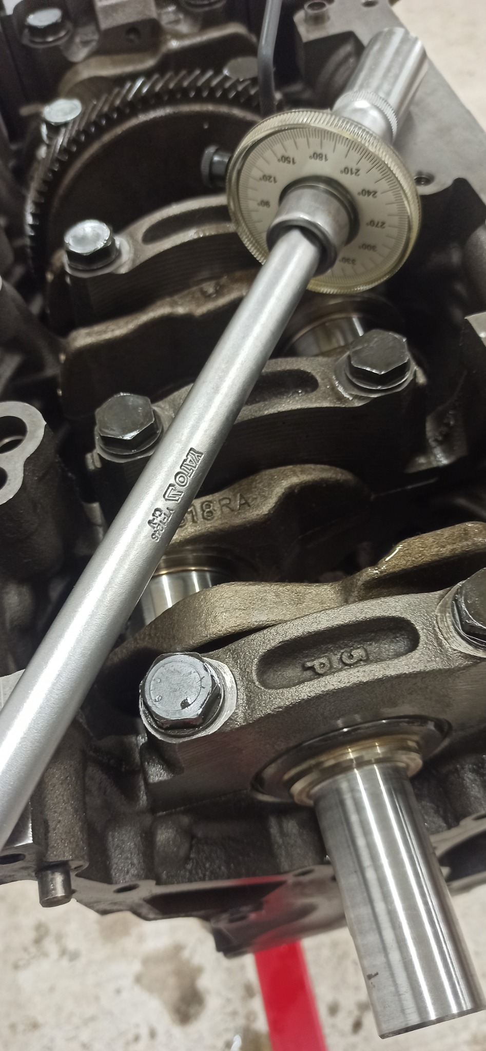 Pomiar wału korbowego silnika narzędziem YATO w Suchedniowie. Widoczne elementy silnika i narzędzie pomiarowe z podziałką kątową. Detal z bliska, oświetlenie warsztatowe.