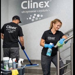 Clinex utrzymanie czystości - Pracownicy w uniformach ClinEx czyszczą schody. Kobieta przeciera poręcz, mężczyzna myje podłogę mopem. Widoczny wózek ze środkami czystości i logo firmy na ścianie.