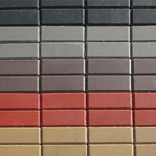 Równy rząd ułożonych obok siebie prostokątnych elementów nawierzchni w różnych odcieniach szarości, brązu, czerwieni i beżu, tworzących mozaikę kolorów.