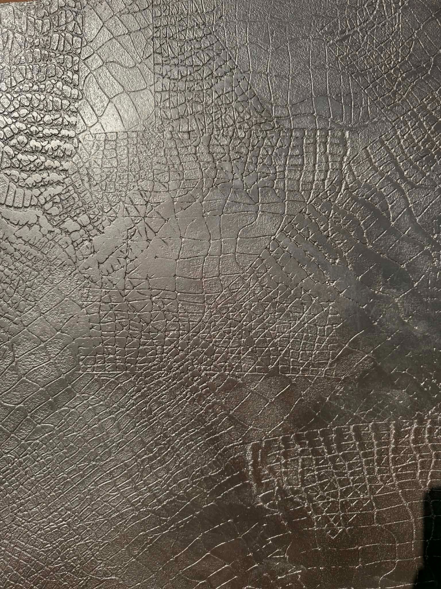 Brązowa ściana z unikalną fakturą imitującą skórę krokodyla, z wyraźnymi pęknięciami i nierównościami, tworzącymi trójwymiarowy efekt wizualny.