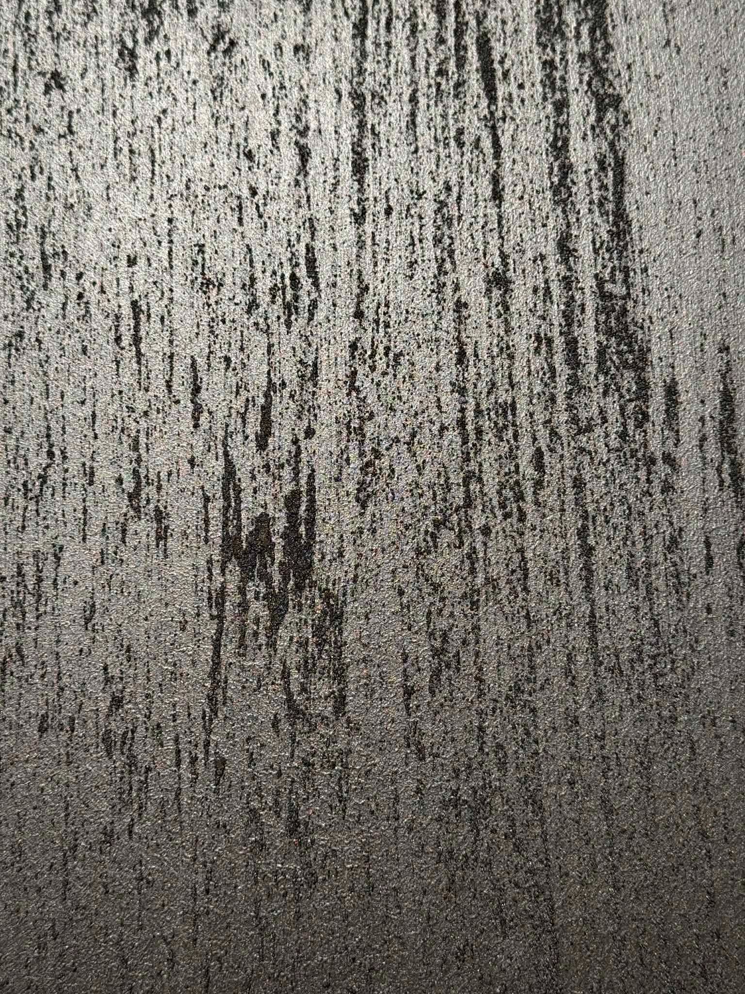 Szara ściana z wyraźną fakturą i pionowymi, ciemniejszymi smugami, przypominająca efekt dekoracyjny po malowaniu.