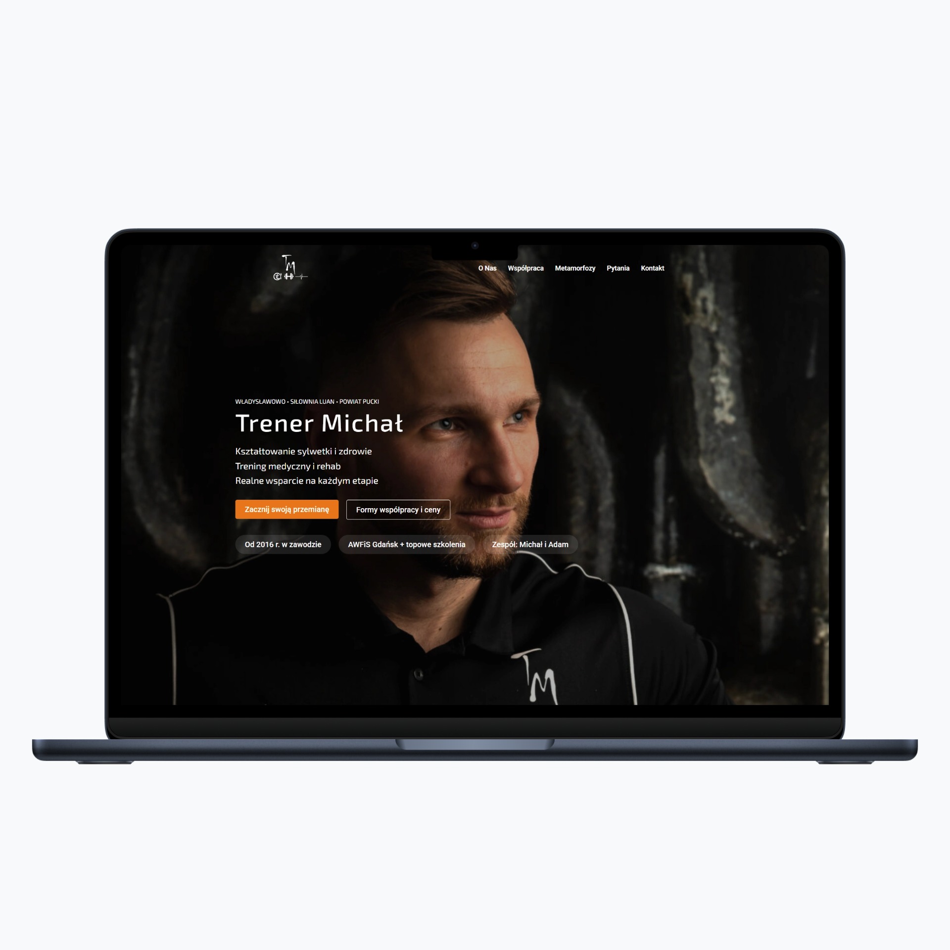 Laptop wyświetla stronę internetową trenera personalnego Michała, z jego zdjęciem i ofertą: kształtowanie sylwetki, trening medyczny i rehab. Widoczne logo firmy.
