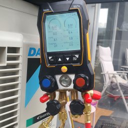 MKDienstleistungen Sp. z o.o. - Diagnostyka klimatyzacji w Gdyni: Manometr cyfrowy Testo 557s podłączony do klimatyzatora Daikin Inverter. Widoczne węże i zawory, wskazania ciśnienia i temperatury.