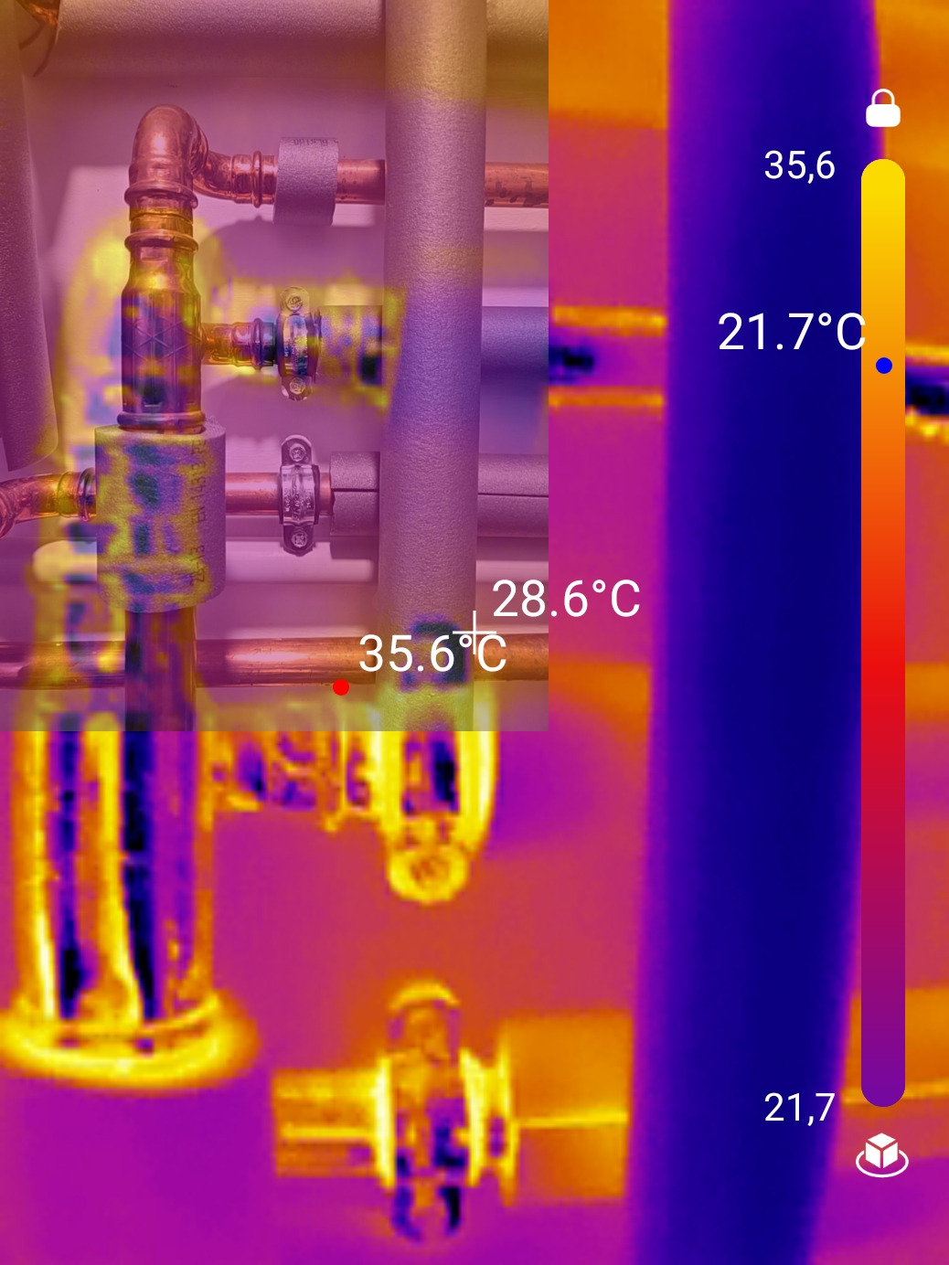 Termowizyjne ujęcie instalacji hydraulicznej z widocznymi temperaturami rur. Detekcja ciepła na złączkach i rurach w odcieniach fioletu, żółci i pomarańczy.
