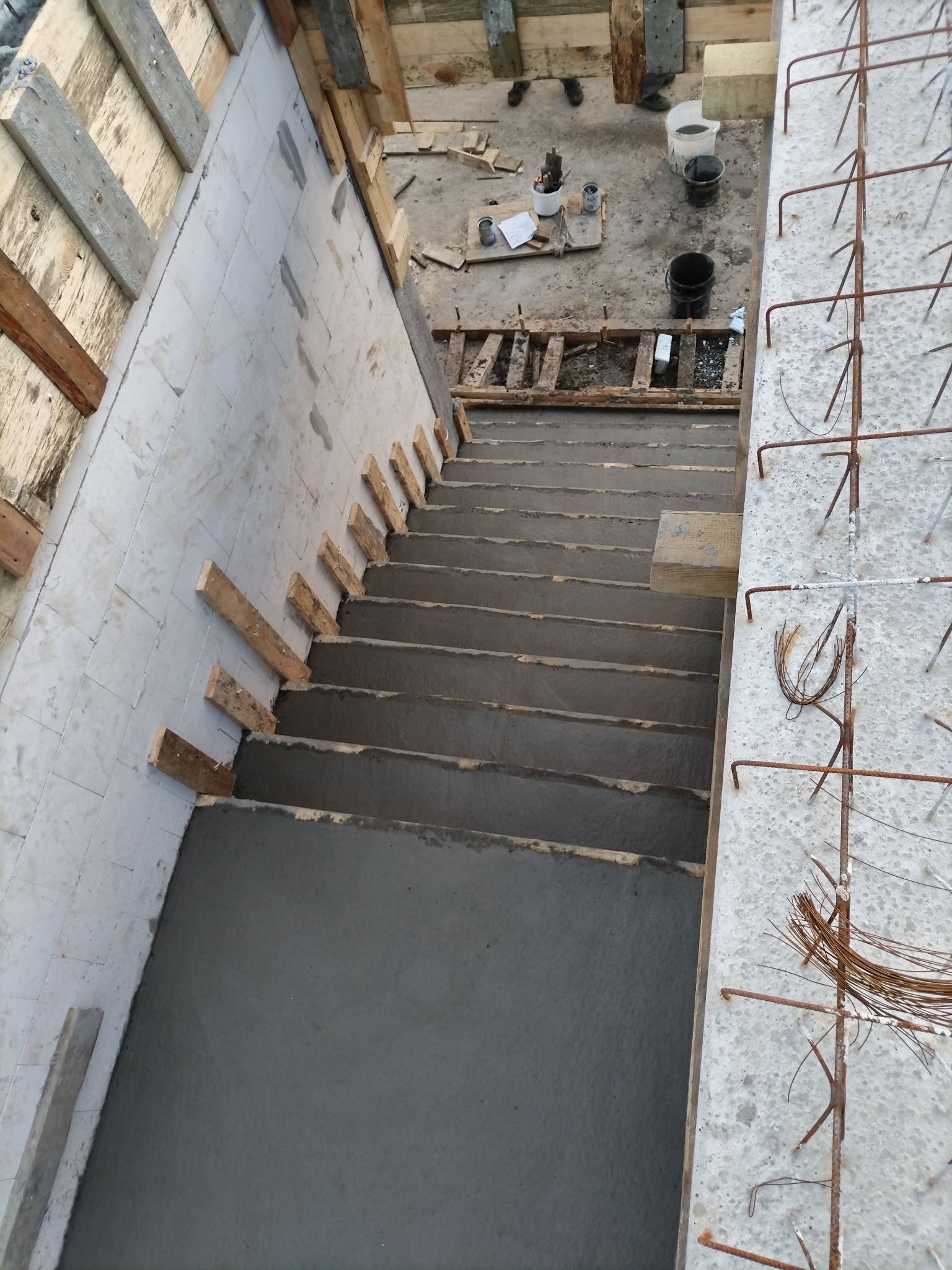 Betonowe schody w trakcie budowy z widocznym zbrojeniem i szalunkiem. Surowy stan, widok z góry.