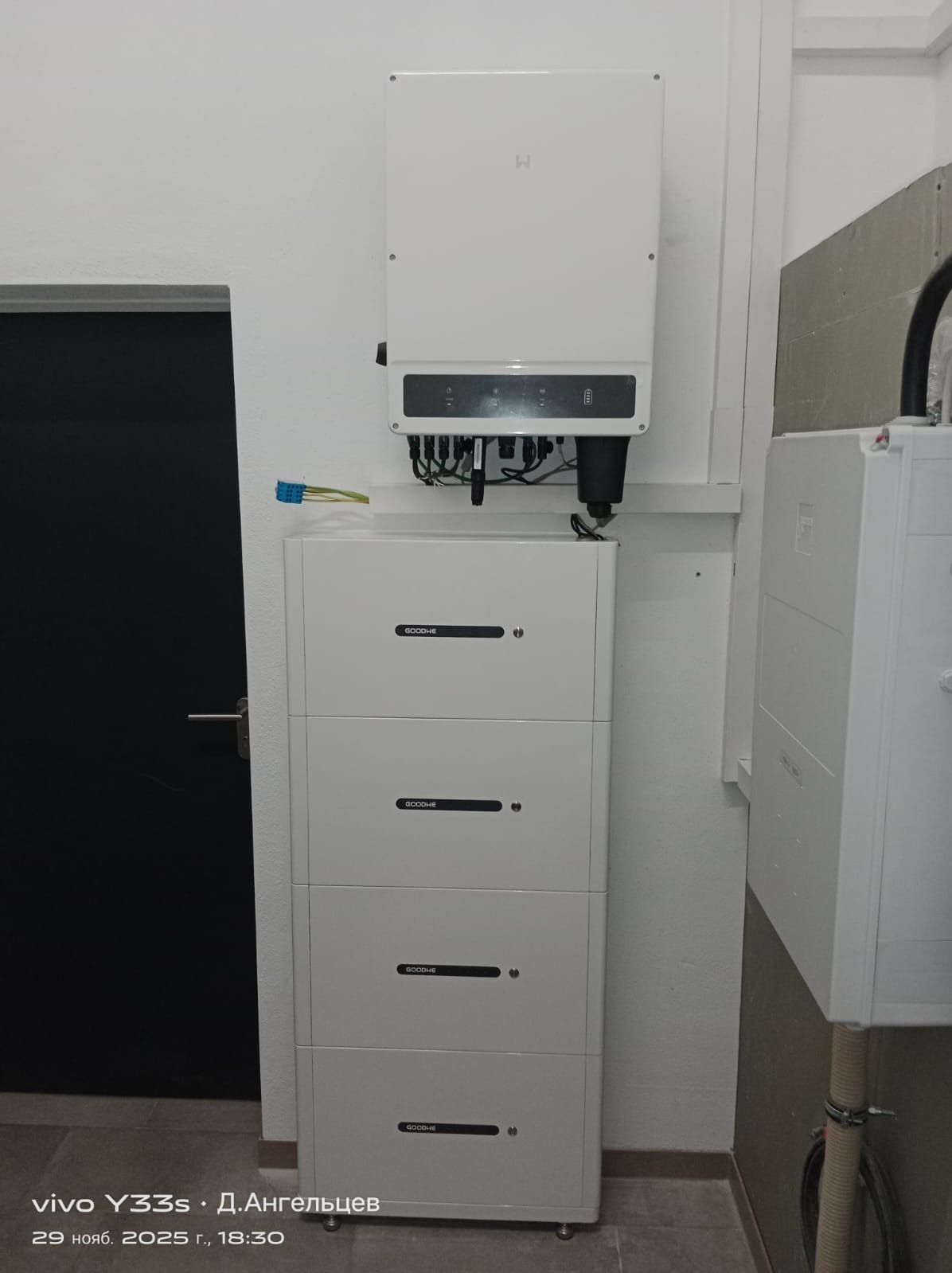 Biała instalacja fotowoltaiczna z inwerterem i bateriami, zamontowana w pomieszczeniu. Widoczne kable i złącza. Minimalistyczny design.