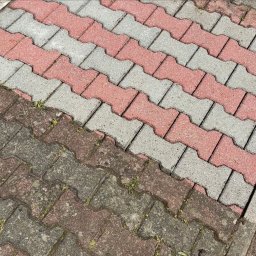 HydroEfekt - Karol Wojtowicz - Częściowo wyczyszczona kostka brukowa w odcieniach szarości i czerwieni, widoczne różnice w kolorze i czystości, diagonalne ułożenie kostki.