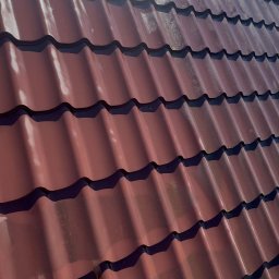 HydroEfekt - Czerwona, błyszcząca blachodachówka po umyciu, widoczna pod kątem. Na powierzchni widoczne refleksy światła słonecznego. Czysty dach z blachy.