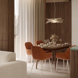 Martyna Koperska Wnętrza - Stylowa jadalnia w Rzeszowie: okrągły stół z nakryciem, pomarańczowe krzesła na białych nogach, designerska lampa i drewniane panele ścienne.