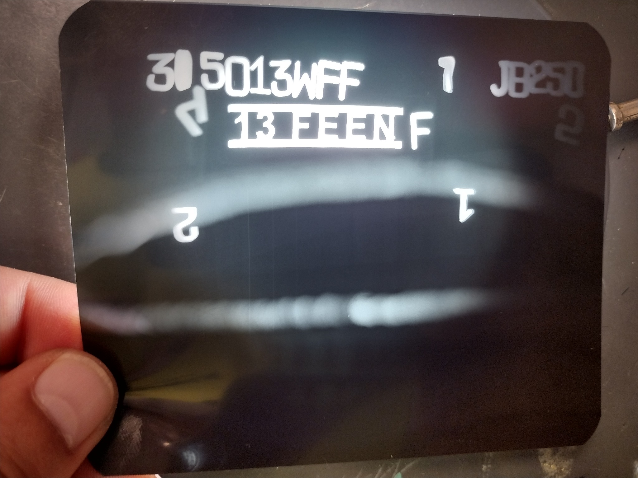 Radiogram spoiny z widocznymi numerami seryjnymi i oznaczeniami, trzymany w dłoni. Kontrola jakości spoin.