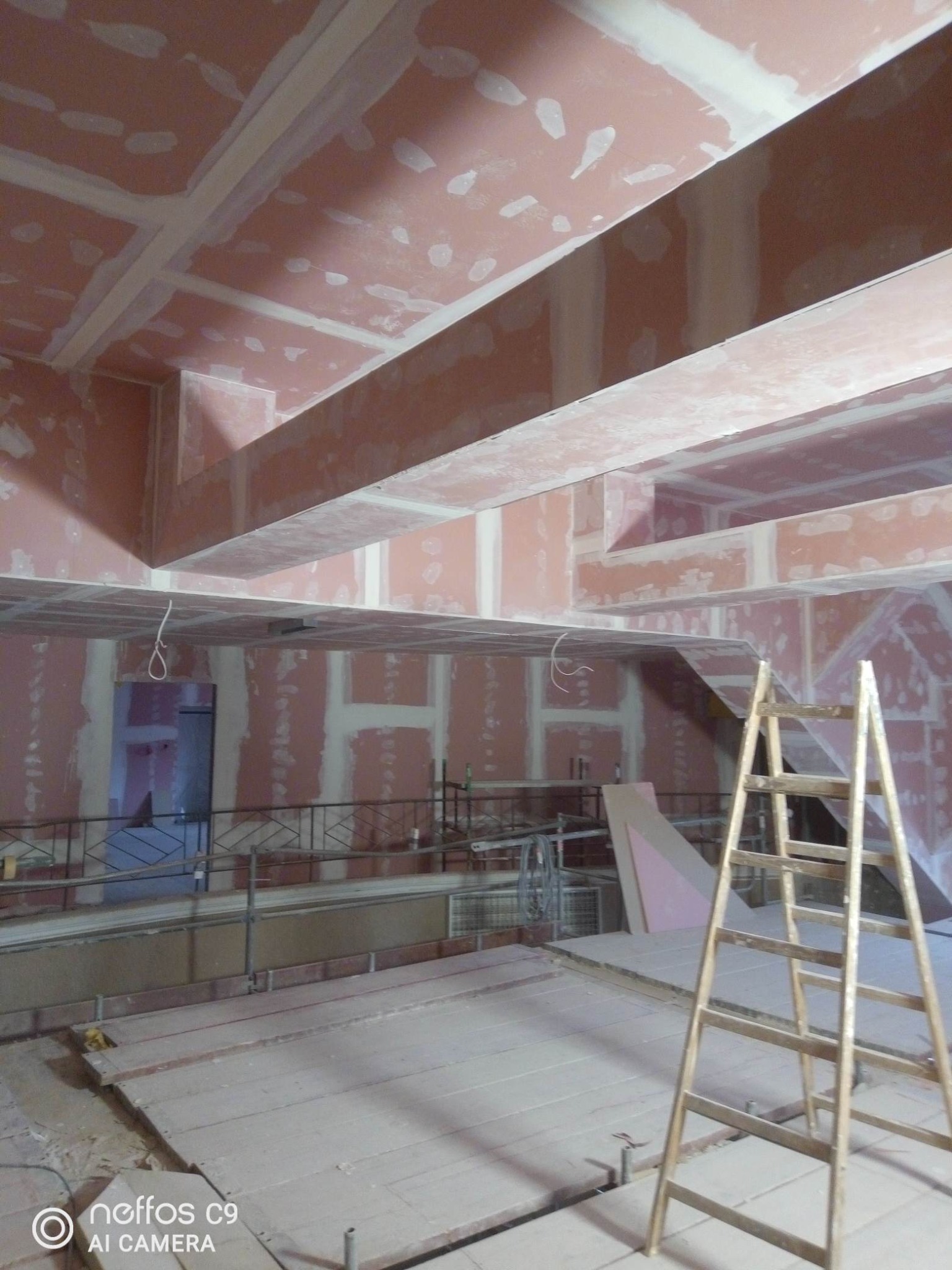 Sufit i ściany w trakcie prac wykończeniowych z płyt kartonowo-gipsowych, widoczna drabina i elementy konstrukcyjne. Surowe wykończenie, przygotowanie do malowania.