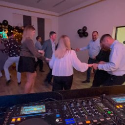 MIKO Y - Parkiet taneczny z bawiącymi się ludźmi i sprzętem DJ-skim Pioneer w pierwszym planie, oświetlony fioletowym światłem.