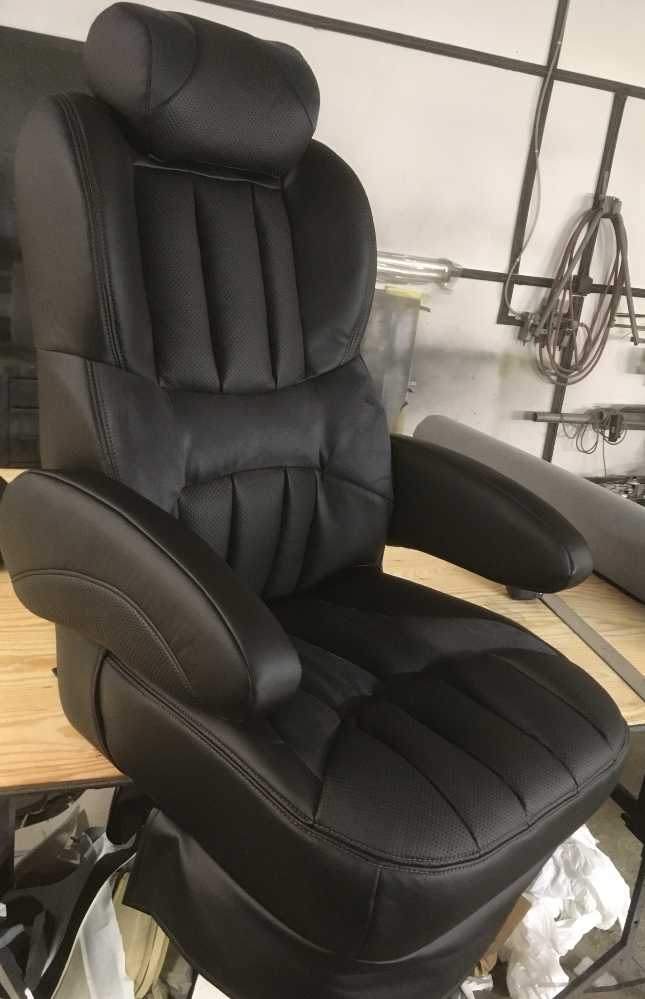 Odnowione, czarne skórzane siedzenie samochodowe z zagłówkiem, po renowacji tapicerskiej w Szczecinie. Widoczne detale przeszyć i perforacji.