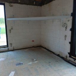 Borys Sanchuk - Wnętrze w trakcie budowy z zamontowaną metalową konstrukcją pod schody lub balustradę, widoczne instalacje elektryczne i hydrauliczne w surowym stanie.