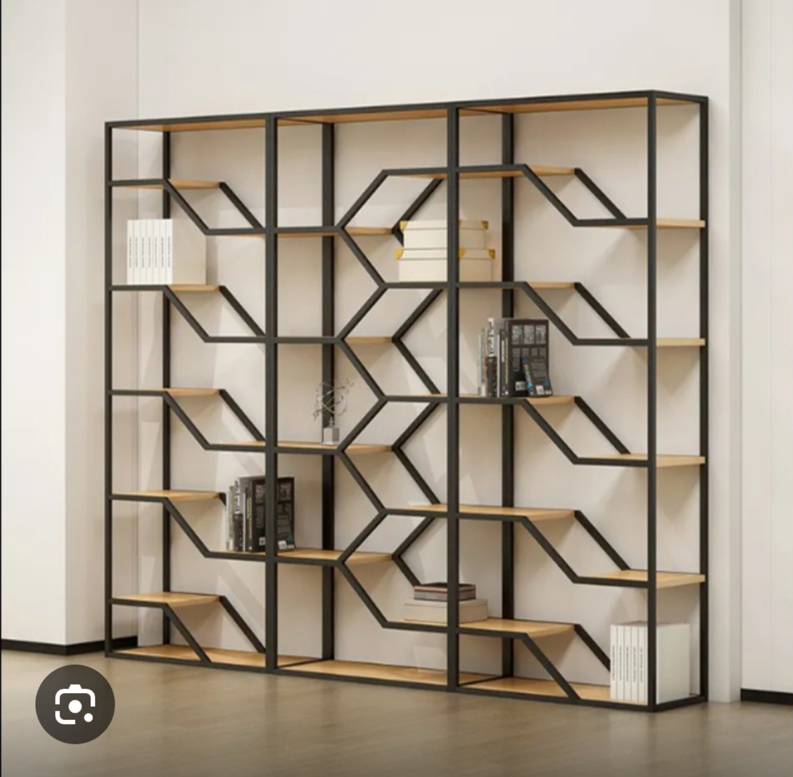 Metalowy regał na książki o geometrycznym wzorze, z drewnianymi półkami, ustawiony na tle białej ściany. Nowoczesny design.