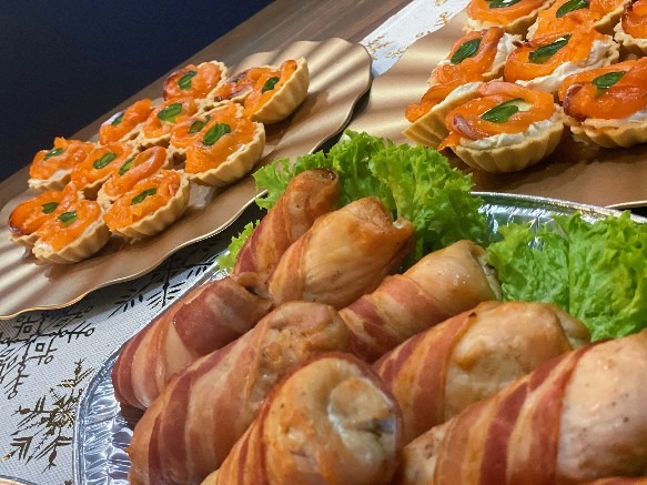 Elegancko podane tartaletki z łososiem i roladki z kurczaka owinięte boczkiem na srebrnych paterach, dekorowane sałatą. Catering na przyjęcie.
