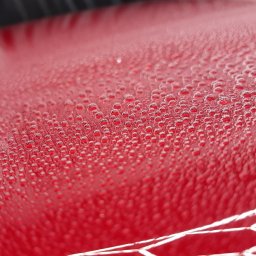 Izdebski Studio - Auto Detailing Warszawa - Czerwony lakier auta po nałożeniu powłoki hydrofobowej w Warszawie. Widoczne krople wody na powierzchni, świadczące o właściwościach ochronnych.