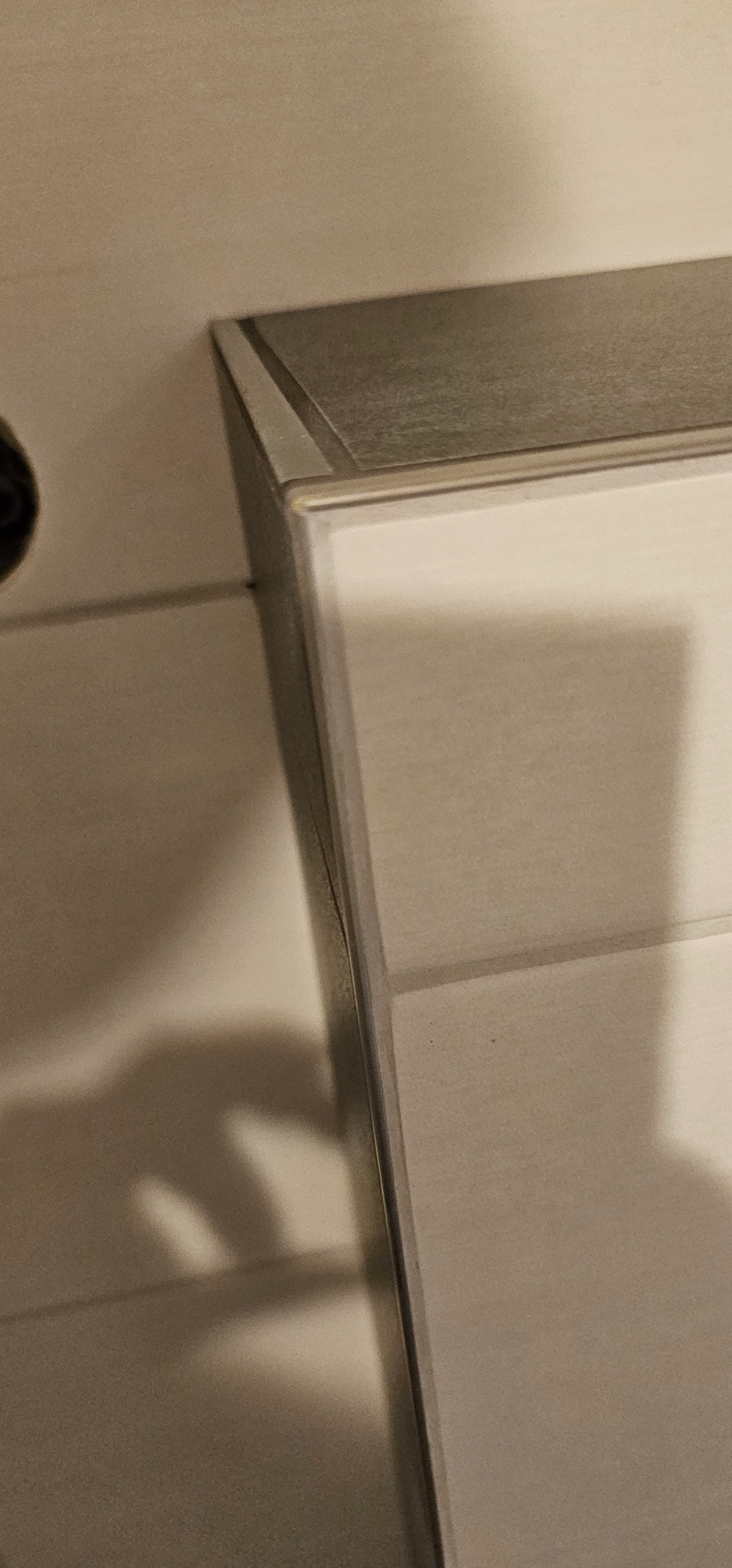 Detal wykończenia ściany z płytami, widoczny profil aluminiowy i białe płyty. Ujęcie z bliska, podkreślające precyzję wykonania.