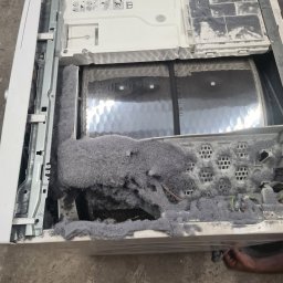 MAGIK AGD - Otwarta pralka z nagromadzeniem szarego pyłu i włókien wewnątrz bębna, ukazująca stopień zużycia i potrzebę czyszczenia lub naprawy.