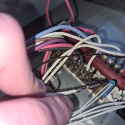 MAGIK AGD - Zbliżenie na rękę serwisanta pracującego nad podłączeniem przewodów wewnątrz urządzenia AGD. Widoczne kolorowe kable i złącza.