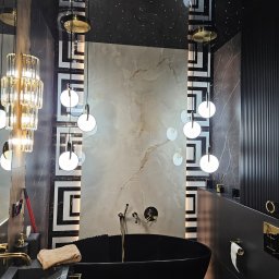 Geblon - Luksusowa łazienka w ciemnej tonacji z wolnostojącą wanną, marmurowymi płytkami i dekoracyjnym oświetleniem sufitowym imitującym gwiazdy. Geometryczne wzory na ścianach.