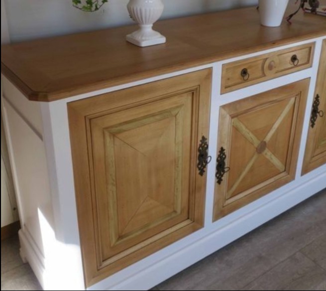 Drewniany kredens w stylu rustykalnym z jasnym blatem i białymi bokami, zdobiony geometrycznymi wzorami na frontach drzwiczek i ciemnymi uchwytami.
