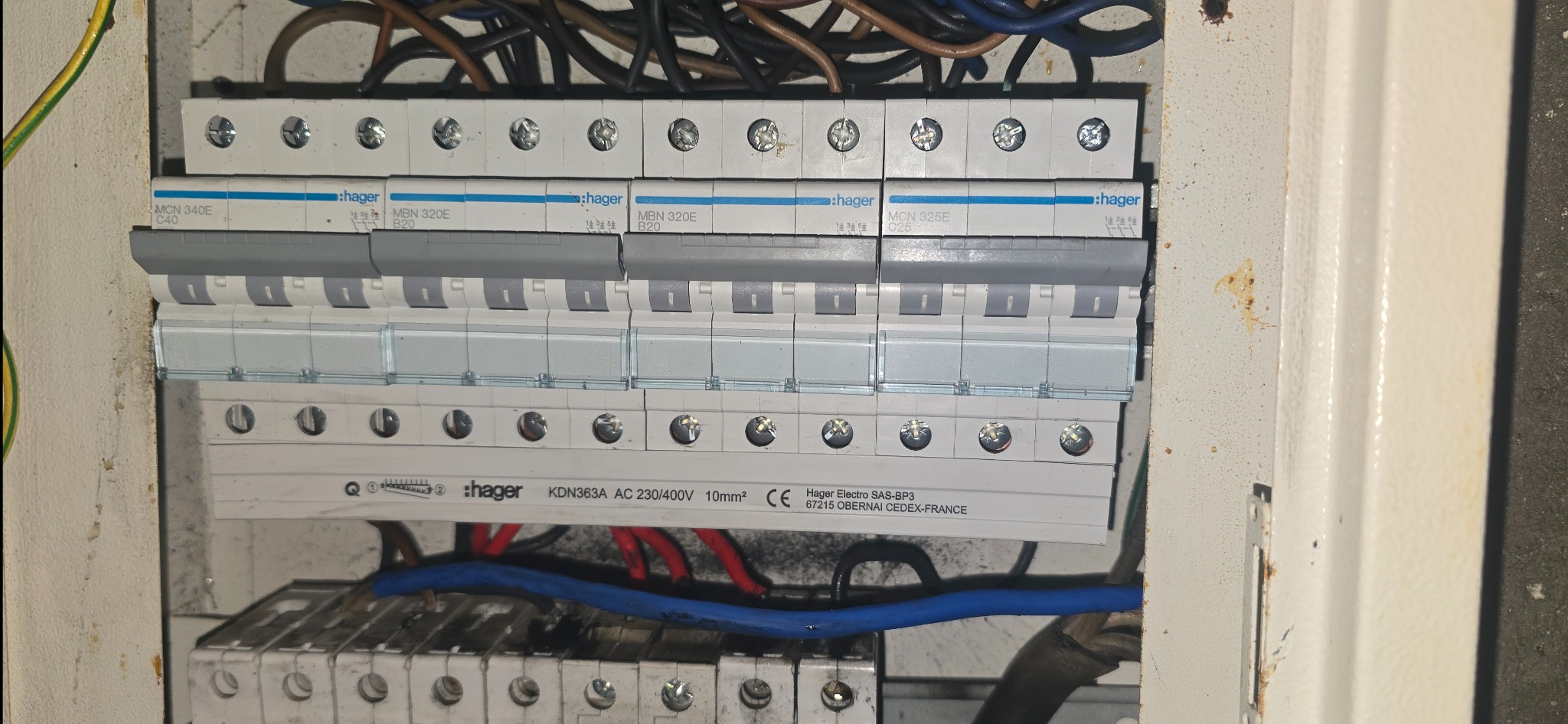 Rozdzielnica elektryczna marki Hager z zainstalowanymi bezpiecznikami i przewodami. Widoczne oznaczenia i specyfikacje techniczne na urządzeniach.