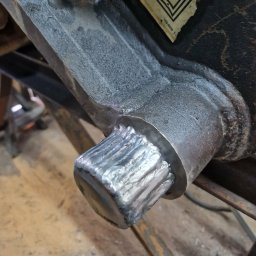 KAMIL SZCZECHURA - Detal spawu na metalowej konstrukcji. Widoczne ślady po spawaniu i fragment etykiety. Bliskie ujęcie na łączenie elementów.