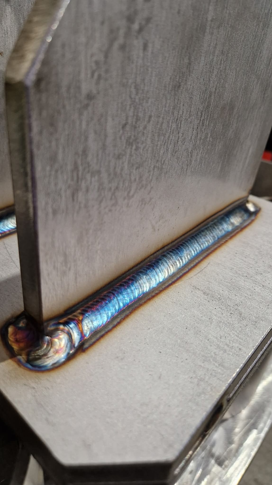 Precyzyjne, barwne spoiwo na metalowej konstrukcji. Widoczne detale i wysoka jakość wykonania. Spawanie metodą TIG z efektem tęczy na spoinie.