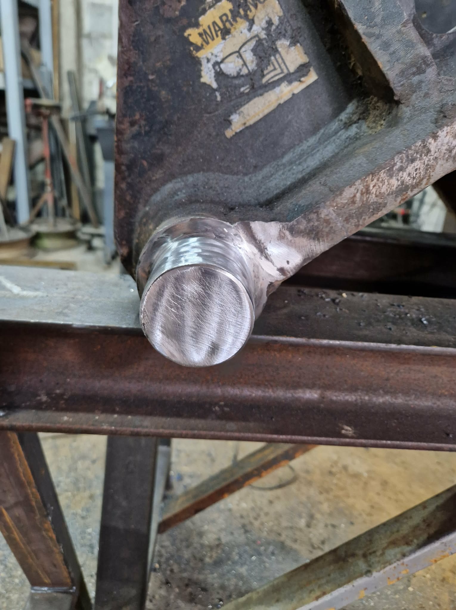 Detal spoiny na metalowej konstrukcji, widoczne ślady obróbki, surowe wykończenie, warsztatowe tło. Precyzyjne łączenie elementów.