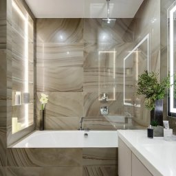 Artem Kobylianskyi - Elegancka łazienka z wanną, płytkami imitującymi marmur i oświetleniem LED. Minimalistyczny design z akcentami roślinnymi i szklanymi półkami.
