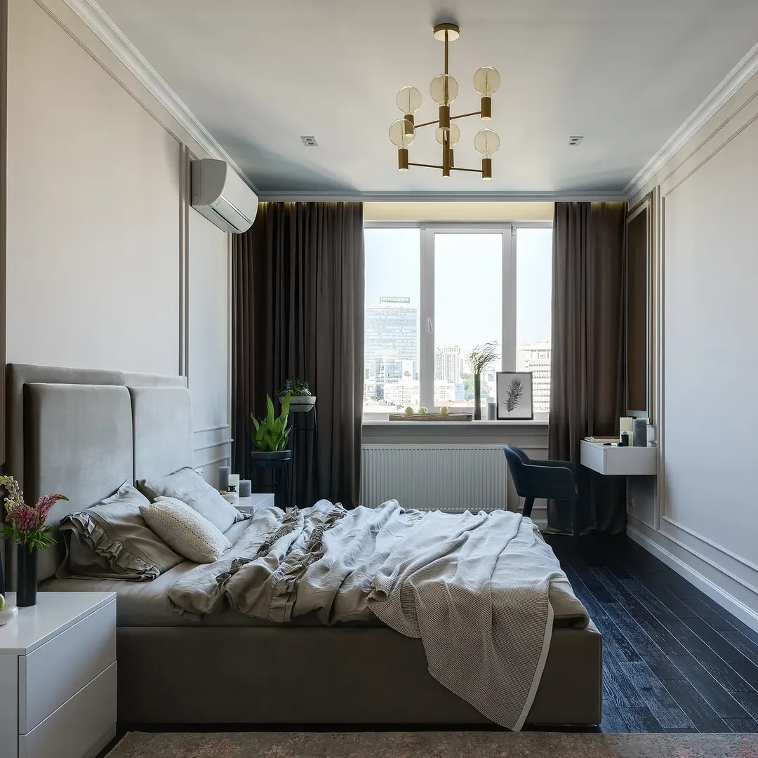 Nowoczesna sypialnia z dużym łóżkiem, ciemną podłogą i oknem z widokiem na miasto. Minimalistyczny design, stonowana kolorystyka, klimatyzacja na ścianie.