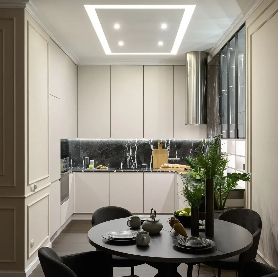 Elegancka kuchnia z marmurowym blatem i oświetleniem LED. Okrągły stół z zastawą i roślinami dodaje przytulności. Nowoczesny design z dbałością o detale.