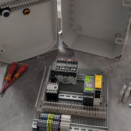 ELITA - TECH Mateusz Pawlak - Rozdzielnica elektryczna w trakcie montażu, widoczne elementy sterujące, przewody i narzędzia. Otwarta obudowa rozdzielnicy z widocznymi elementami wewnątrz.