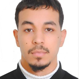 SanTechnology - Portret młodego mężczyzny z brązowymi oczami i ciemnymi włosami, ubrany w biały golf i czarną marynarkę, na białym tle.