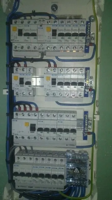 Rozdzielnica elektryczna z zamontowanymi bezpiecznikami EATON i licznikiem Legrand, okablowanie w listwach. Widok z bliska na instalację w skrzynce.