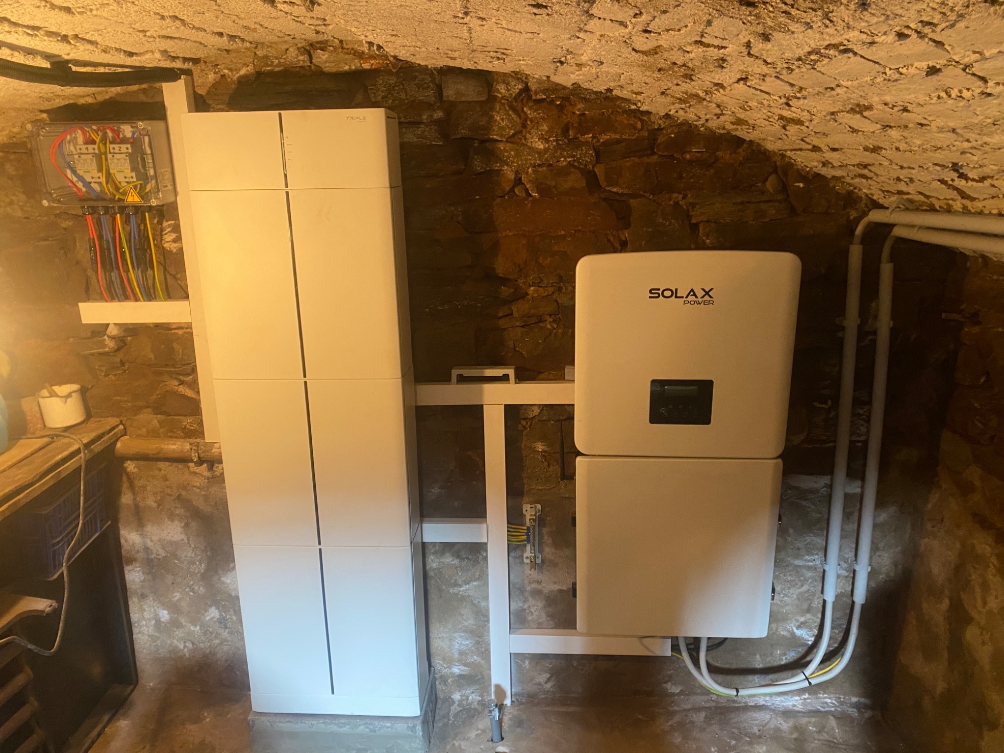 Instalacja fotowoltaiczna Solax Power w piwnicy o kamiennych ścianach w Warszawie. Widoczna skrzynka elektryczna i akumulator. Nietypowe umiejscowienie.