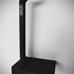 Kamil Czernik - Czarny, matowy stojak na słuchawki z widocznym wzorem geometrycznym, wydrukowany w technologii addytywnej. Minimalistyczny design na tle jasnej ściany.