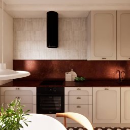 PROJEKTOWANIE WNĘTRZ Adrianna Lis - Nowoczesna kuchnia z beżowymi szafkami, miedzianym blatem i czarnym okapem. Minimalistyczna lampa nad stołem. Widok na okno z roletą i dekoracyjną podłogę.