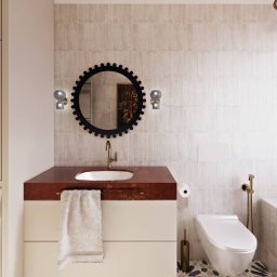 PROJEKTOWANIE WNĘTRZ Adrianna Lis - Nowoczesna łazienka z umywalką na blacie z terazzo, okrągłym lustrem z dekoracyjną ramą i złotą armaturą. Widoczna pralka i płytki w odcieniach beżu.